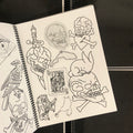 Inside pages of The Black Book featuring line drawings of skulls in the traditional style.