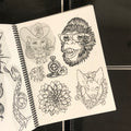 Inside pages of The Black Book featuring line drawings of animals heads such as a cowboy cat lady, a chimpanzee wearing sunglasses, and a chihuahua surrounded by a filigree border. Also featured a flower and smaller drawings of a compass and rose, and a surfboard and waves.