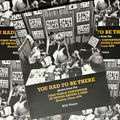 Front cover of "You Had to Be There" by Billy Tinney featuring a vintage photograph of tattooers working in a booth surrounded by flash art.