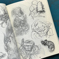 Inside pages of unrefined by Evan Griffiths featuring line drawings and sketches of animals in the Japanese style, including crabs, a cat, a mouse, and a fight between a snake and a lion.