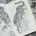 Inside pages of Japanese Tattoo Outlines by Leo Barada featuring a line drawing of a tiger descending a formation with a waterfall and waves.