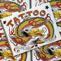 Front cover of Mark Peoples Tattoo Flash Volume 1 featuring a dragon in red, yellow, black, and orange with text and banners. 
