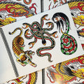 Inside pages of Mark Peoples Tattoo Flash Volume 1 featuring a multi headed snake in green, red, and yellow, a woman's head with a snake body, and a gold tiger in traditional style & colors. 