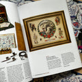 Inside pages of The Tattoo Catalogue 2024 featuring a framed flash sheet with Pharaoh's Horses and Native American imagery. The opposite page showcases various vintage equipment, including a tattoo machine, ink bottles, and design sheets. 