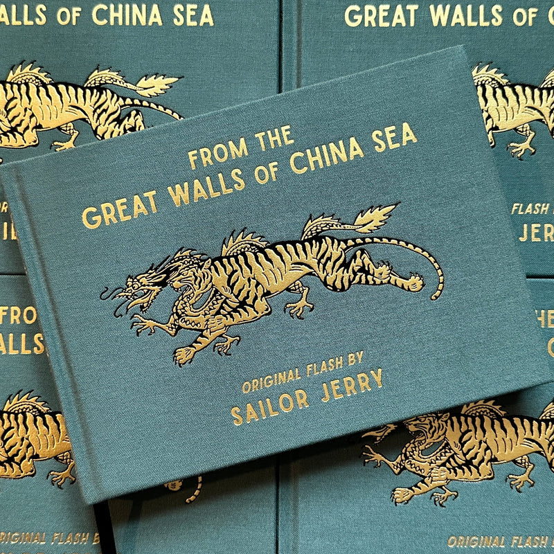 Front cover of Sailor Jerry's 'From the Great Walls of China Sea' featuring a tiger running with a dragon, embossed in gold. 
