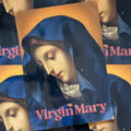 Front cover of 'Virgin Mary', featuring the face of the Virgin Mary looking downward and wearing a blue cloak. 