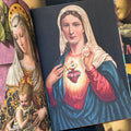 Inside pages of 'Virgin Mary', featuring the Virgin Mary looking forward with a sacred heart on her chest, pulling her cloak aside and holding up her head wrap with one hand. 