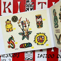 Inside pages of Buddy Holiday Tiki Tattoo Designs Vol. 3 featuring flash paintings of a seahorse, a flaming tiki torch, a sun, tiki figures, and the word aloha, all painted in rainbow colors.