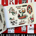 Inside pages of Buddy Holiday Tiki Tattoo Designs Vol. 3 featuring flash paintings of a skull drink with an umbrella in it, a bird surfing next to a volcano, a monkey hanging upside down holding a drink, a tiki mask on the right, a drink with a skull in it and playing cards, and the words 'surfin bird', all painted in red, green, and gold.