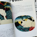 Inside pages of, 'Cats in Ukiyo-e', featuring a circular panel of a cat laying down on a robe, with English and Japanese text above it 