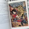 Inside pages of, 'Cats in Ukiyo-e', featuring a Samurai on a ship being attacked by a big cat, trying to fight it off with his hands 