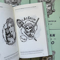 Inside pages of, 'Russian Criminal Tattoo Encyclopaedia Vol. 2', featuring a skull with hair, a shovel, ice pick, and barbed wire around it, with a Russian text above it