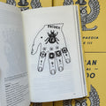 Inside pages of, 'Russian Criminal Tattoo Encyclopaedia Vol. 3', featuring a drawing of a hand with hand tattoos of a beetle, some flowers, 1954 on the knuckles, and 4 rings on with different symbols