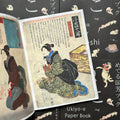 Inside pages of 'Cats by Kuniyoshi', featuring a Geisha woman squatting on the floor with a white cat licking itself beside her
