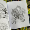 Inside pages of The Dragon Sketchbook by Erik Rieth, a line drawings and sketches tattoo book, featuring a fiery dragon and other dragon depictions.