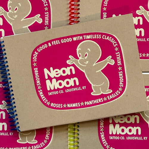 Cover of 'Neon Moon Tattoo', featuring a brown paper cover in a transparent blue spiral bound, with a pink circular center piece that says 'Neon Moon' and casper the ghost standing beside it.