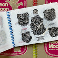Inside pages of, 'Neon Moon Tattoo', featuring 5 bulldog heads in black and grey drawn on vellum paper.