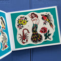 Traditional tattoo flash sheet from 'Everything That Burned' tattoo book by Jeff P. with a peacock pin-up girl, scorpion, rose, a bird, and yellow flowers.