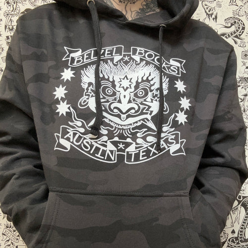 front of a black and grey pullover camouflage hoodie, featuring a white screenprinted belzel books logo