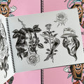 Inside pages of Tattooing Flash Book by Frank Ball featuring a lady-head design split by a rose, revealing a skull; a rose intertwined between an open blade in the shape of a lady boot; and a Chicana lady head, with half the face showing the skull. 