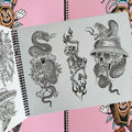 Inside pages of Tattooing Flash Book by Frank Ball featuring two skull designs with intertwined snakes, and one dancing skeleton with tribal flames.