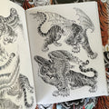 Inside pages of The Tiger Book by Tim Lehi featuring black and grey illustrations of flying tigers.