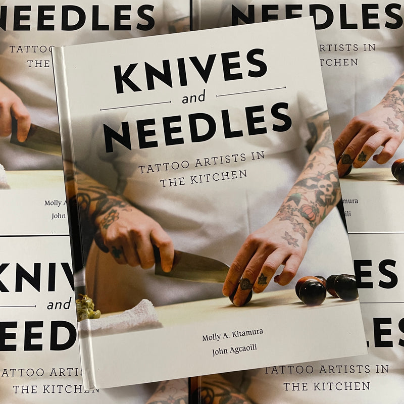 Front cover of Knives and Needles: Tattoo Artists in the Kitchen by Molly Kitamura & John Agcaoili featuring tattooed chef's hands cooking on cover.