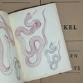 Inside pages of Garden of Snakes by Eckel featuring  detailed line drawings of snakes in red or black.