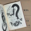 Inside pages of Garden of Snakes by Eckel featuring a black and white snake weaving through flowers.