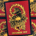 Front cover of Heinz Sketchbook 2020 featuring a panther holding a skull with flowers and surrounded by flames in traditional style. The image is yellow with a red background and black border.