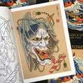 Inside pages of Daniele Tonelli - Japanese Flash & Lines featuring a white hannya mask with a veil, impaled with a red and white cane and intertwined with white and green decorative rope on a light tan background with a white border.