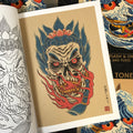 Inside pages of Daniele Tonelli - Japanese Flash & Lines featuring a skull version of a hannya mask in flames with blue traditional hair and a pink lotus flower on top on a light tan background with a white border.