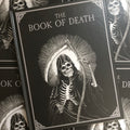 Cover of Mike Destefano - The Book Of Death showing a grim reaper holding a scythe  in the center of the a black background and rays of white extending out behind him. 