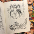 Inside page of Tracy D - Lines Vol.1 showcasing 3 long-haired female figures dressed in headdresses. One is holding a flower, one is holing a trident, and the center is making an "O" shape with her hands. The three of them are above 2 flowers that are joined by string.