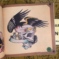 Inside page of Front cover of Jonathan Shaw's - Vintage Tattoo Flash Collection: Skulls Vol.1  highlighting an eagle with a skull in its clutches. The skull has a blank banner handing from its mouth. 