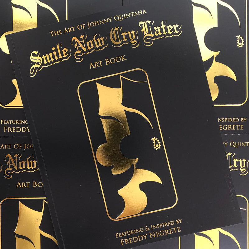 Cover of The Art of Johnny Quintana - Smile Now Cry Later featuring smiling/crying mask outlines, gold lettering, and a black background on a softcover book.